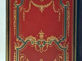 an old book with a red cover and gold decoration on it