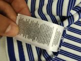 someone is holding a label on a blue and white striped shirt