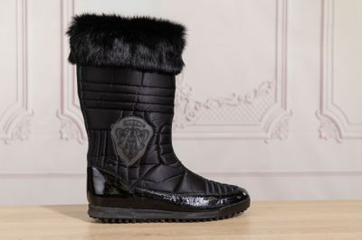 the black boots are on a wooden table in front of a wall