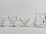 trois verres transparents et un pichet posés les uns à côté des autres sur une surface blanche