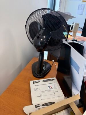 un ventilateur posé sur un bureau en bois à côté d'un ordinateur