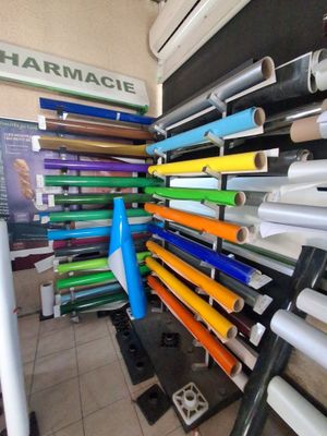 de nombreux rouleaux de papier coloré posés sur un présentoir dans un magasin
