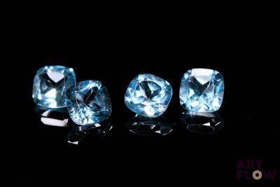 trois pierres précieuses de topaze bleue sont posées sur une surface noire