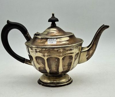 an antique silver teapot with a black handle on a white surface