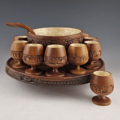 un bol et des tasses en bois posés sur un plateau, accompagnés de cuillères