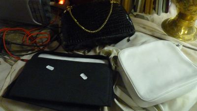 un ordinateur portable et un sac à main posés sur un lit, à côté d'une lampe