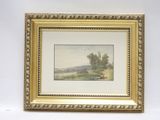 un tableau représentant un paysage, dans un cadre doré, accroché à un mur blanc
