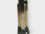 a sculpture of a clock on a stand on a white surface