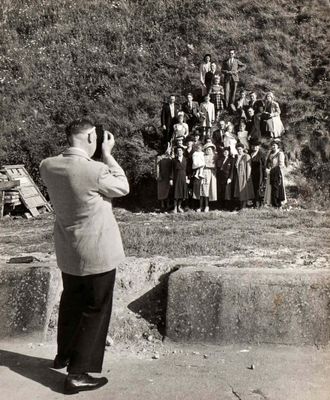 black and white photograph of a man taking a picture of a group of people