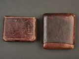 two brown leather wallets sitting on top of a table