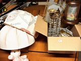 a table with a lamp, a lamp shade, a teddy bear, and other items on it