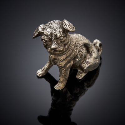 silver figurine of a pug dog on a black surface