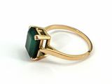 a close up of a gold ring with a green stone