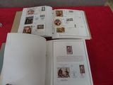 un livre ouvert posé sur une table rouge, sur laquelle se trouvent des timbres