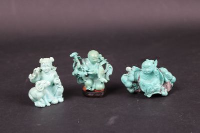three small figurines of people sitting on a black surface