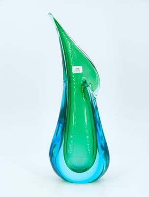 Le vase en verre vert et bleu est posé sur une surface blanche.