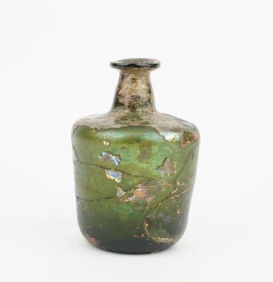 a green glass bottle that is sitting on a white surface
