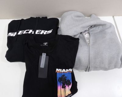 three t - shirts and a hoodie sitting on a table