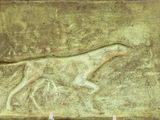 painting of a dog running in a field of grass on a plaque
