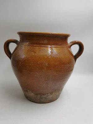 un vase marron muni de deux anses, sur un fond blanc