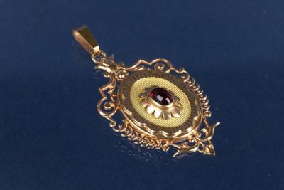 un pendentif en or orné d'une pierre rouge au centre