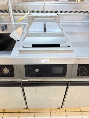 plan de travail en acier inoxydable dans une cuisine professionnelle équipée d'une cuisinière et d'un four