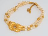 a close up of a necklace with pearls and gold