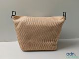 beige woven bag with black handles on a white surface