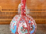 a red vase sitting on top of a wooden table