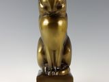 bronze statue of a cat sitting on a wooden block