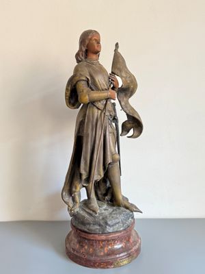 statue d'un homme tenant un oiseau, posée sur un socle posé sur une table