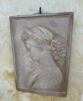 an old picture of a woman ' s head hanging on a wall