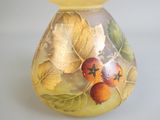 un vase jaune orné de feuilles et de baies peintes