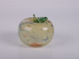 une pomme en verre surmontée d'une feuille verte