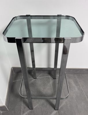 une table en verre avec un piètement en métal posée sur un sol carrelé