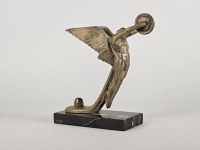 une statue en bronze représentant un oiseau muni d'une clochette, posée sur un socle en marbre