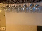 many wine glasses hanging from the ceiling in this kitchen