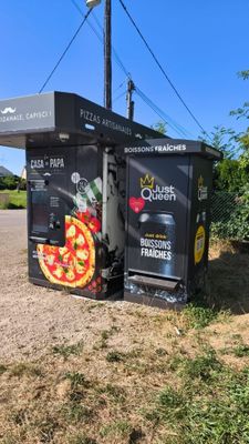 une boîte noire sur laquelle est dessinée une pizza, posée sur le bord de la route