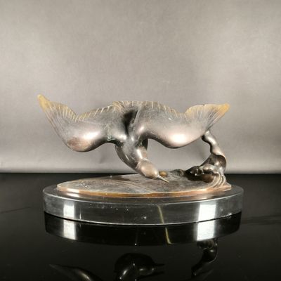 statue of a cat with a fish on a base on a table