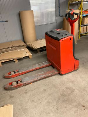 un chariot élévateur rouge dans un entrepôt rempli de cartons