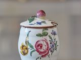 a small white jar with flowers on it on a table