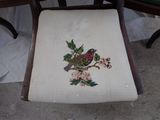 a small bird sitting on a chair with a flower on it