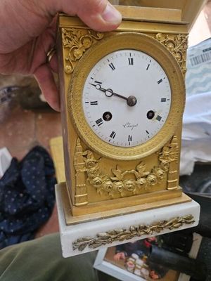 une personne tenant une petite montre en or dans la main