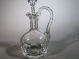 une bouteille en verre transparent munie d'une anse, posée sur une table