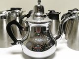 four silver teapots and one silver teapot on a white table