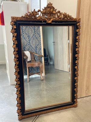 un grand miroir posé par terre à côté d'une chaise