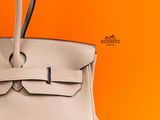 a white purse sitting on top of a table next to an orange box