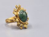 an image of a gold ring with a green stone in the center