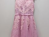 a pink dress hanging on a hanger against a wall