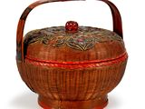 un panier en osier avec une poignée rouge sur fond blanc